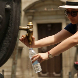 Una persona bebe agua en una fuente de Barcelona para combatir el calor.