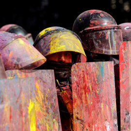 Los Mossos d'Esquadra se parapetan bajo sus escudos manchados por la pintura lanzada por los manifestantes./REUTERS