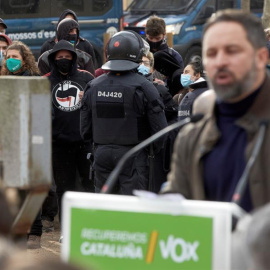 Agentes controlan a un grupo antifascista mientras el líder de Vox, Santiago Abascal (d), interviene en un acto electoral celebrado este sábado en el parque de la Dehesa de Girona.