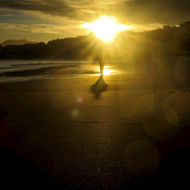 Un hombre observa el amanecer en la playa de Ondarreta de San Sebastián.