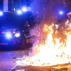 Un furgón de los Mossos d'Esquadra pasa junto al fuego durante los altercados al finalizar la movilización convocada por la ANC y otras entidades soberanistas. - EFE