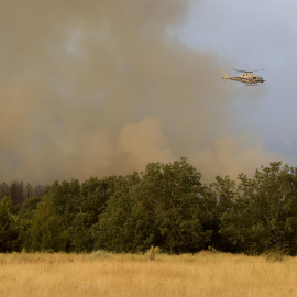Un helicóptero trabaja en el incendio de Monsagro que los vientos cambiantes y el fuerte calor mantienen activo y dificultan su estabilización, este viernes en Salamanca.
