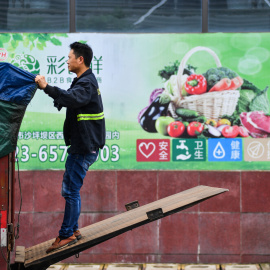 Un trabajador ajusta la lona de su camión junto a un supermercado en la localidad china de Chongqing. REUTERS/Stringer