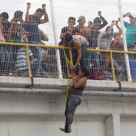 Una migrante trata de escalar el puente que cruza el río que une México con Honduras.REUTERS/Edgard Garrido