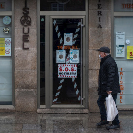 Un hombre camina junto a un bar cerrado en Xinzo de Limia, Ourense.
