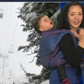 La presentadora Susan Martin con su hijo a la espalda dando el parte meteorológico. Fuente: facebook.