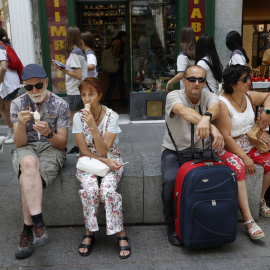 Varios turistas descansan en un banco de granito en el centro de Madrid. EFE/ Mariscal