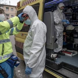 Un trabajador de una UVI móvil del SUMMA 112 se viste con un EPI con la ayuda de otro trabajador durante una jornada de trabajo, en Madrid.