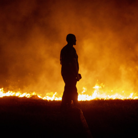 Un vecino ante las llamas mientras colabora en las labores de extinción del incendio de Cures, en Boiro, A Coruña.