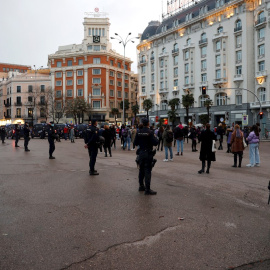 Efectivos policiales vigilan a asistentes a una sentada improvisada en la plaza de Neptuno de Madrid.