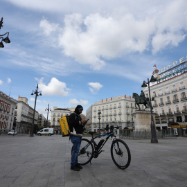 Un repartidor de la empresa Glovo mira su teléfono en la Puerta del Sol.