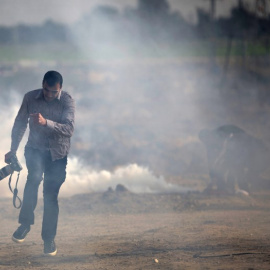 Un fotógrafo palestino trata de evitar el gas lacrimógeno lanzado por las fuerzas israelís. MOHAMMED ABED/AFP/Archivo