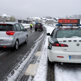 Efectivos de la Guardia Civil trabajan para descongestionar una retención por nieve en la autovía A-52, en Ourense. Las nevadas y las bajas temperaturas registradas en las últimas horas han provocado complicaciones desde primera hora de este sábado en