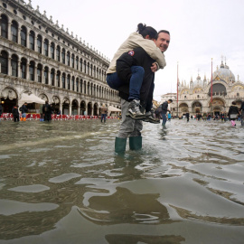 Un hombre carga a sus espaldas con su hija en la Plaza de San Marco de Venecia, inundada como consecuencia del temporal de lluvias. Andrea Merola/EFE