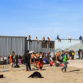 Integrantes de la primera caravana de centroamericanos escalan el muro fronterizo en Tijuana. (JOEBETH TERRIQUEZ | EFE)
