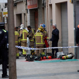 Bomberos y Mossos d'Esquadra permanecen en las inmediaciones del inmueble situado en la calle Riera Blanca de L'Hospitalet de Llobregat (Barcelona) donde esta mañana se ha declarado un incendio en el que un adulto y un menor han muerto y otro menor ha re