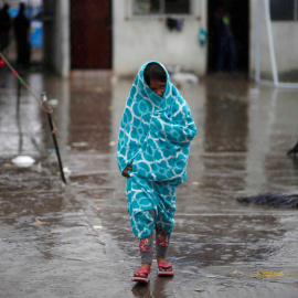 Una niña centroamericana que viaja en una caravana de migrantes, envuelta en una toalla para protegerse de la lluvia en un refugio de Tijuana. / REUTERS - MOHAMMED SALEM