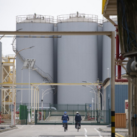 Dos trabajadores montan en bicicleta en la planta de regasificación de Enagas en Barcelona, ​​la más antigua de Europa continental.