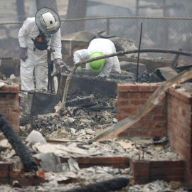 Miembros de un equipo de rescate buscan restos humanos en una de las miles de casas quemadas en California. (TERRAY SILVESTER)