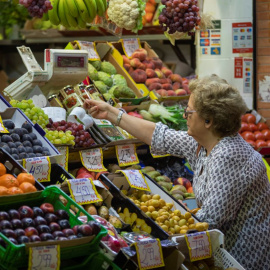 Una mujer compra en uno de los puestos del mercado de abastos de Triana. A 13 de septiembre de 2022, en Sevilla.