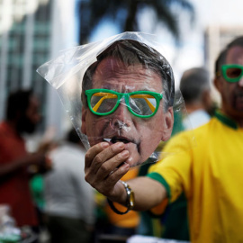 Un vendedor callejero en sao Paulo sostiene una careta con la efigie del candidato ultraderechista Jair Bolsonaro. REUTERS/Nacho Doce