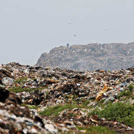 Un hombre recolecta materiales reciclables a medida que el humo se acumula en un vertedero en llamas con motivo del Día de la Tierra, en Calcuta. / Reuters