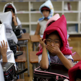 Niños se protegen con capuchas acolchadas en el simulacro de terremoto en un colegio de primaria en Tokio, 1 de septiembre, 2015. REUTERS/Toru Hanai