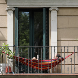 Un hombre tumbado en la hamaca instalada en su balcón durante la cuarentena por el coronavirus. / NACHO DOCE (REUTERS)
