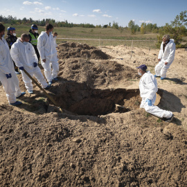 Técnicos forenses trabajan en un lugar de entierro cerca de la ciudad recientemente recuperada de Lyman, en la región de Donetsk.