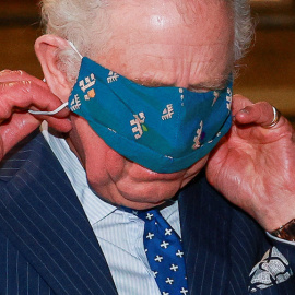  El príncipe Carlos se ajusta el cubrebocas durante una visita oficial en Londres el 14 de diciembre de 2021.- AFP