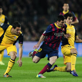 Messi trata de zafarse de Tiago y Koke en la ida de la Champions. JOSEP LAGO / AFP