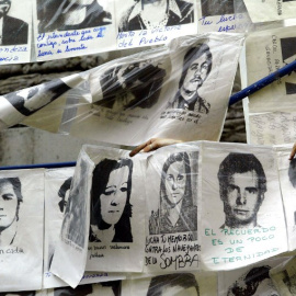 Una mujer cuelga fotografías de desaparecidos durante la última dictadura militar, alrededor de la Piramide de Mayo frente a la Casa de Gobierno, en Buenos Aires, Argentina, el 10 de diciembre de 2003, cuando se cumplen 20 años del retorno 