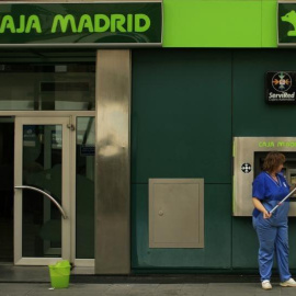 Una empleada limpia la facahda de una oficina de Caja Madrid en Sevilla. REUTERS/Marcelo del Pozo
