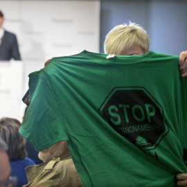 Una activista de la PAH muestra una camiseta alusiva a los desahucios durante intervención de Rajoy en Barcelona./ EFE