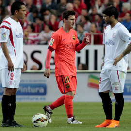 Messi pasa ante los jugadores del Sevilla Bacca y Éver Banega. / EFE