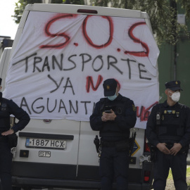 Tres policías junto a una pancarta en las protestas de este sábado en Oviedo, donde diversos colectivos de transporte y ganaderos se manifiestan con motivo de la huelga de transporte en las cercanías del Palacio de Exposiciones donde se cel
