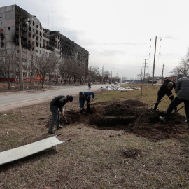 Un grupo de personas cava una tumba en una calle de la ciudad sitiada de Mariupol, Ucrania, 20 de marzo de 2022.