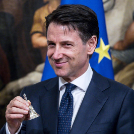 El nuevo primer ministro italiano, Giuseppe Conte, posa con una pequeña campana de plata entregada por el ahora exprimer ministro Paolo Gentiloni (no aparece) para abrir el primer Consejo de Ministros en el Palacio de Chigi, en Roma. EFE