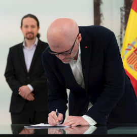 El vicepresidente de Derechos Sociales y Agenda 2030, Pablo Iglesias, observa al secretario general de CCOO, Unai Sordo, durante la firma del acuerdo que prorroga los ERTE por fuerza mayor hasta el 30 de junio. EFE