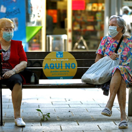 Dos mujeres conversan en un banco de L'Hospitalet (Barcelona) este jueves. EFE/Toni Albir