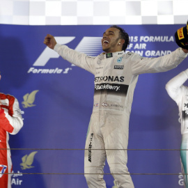 El piloto británico de Fórmula 1 Lewis Hamilton (Mercedes ) celebra en el podio su victoria en la carrera del circuito de Baréin. Por detrás de él has entrado en meta Kimi Raikkonen (Ferrari) y Nico Rosberg (Mercedes). REUTERS/Ahmed Jadalla