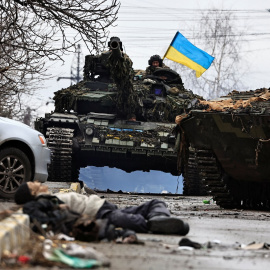 Soldados del ejército ucraniano se sientan en la parte superior de su tanque mientras el cuerpo de un civil yace en la calle en Bucha.