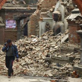 Un hombre llora mientras camina por la calle mientras junto a una estatua de Buda dañada un día después de un terremoto en Bhaktapur, Nepal.- REUTERS / Navesh Chitrakar