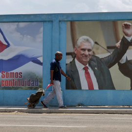 Un hombre camina frente a un fotografía de Miguel Díaz-Canel junto a Raúl Castro, en La Habana (Cuba).