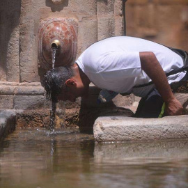 Un hombre se refresca en una fuente pública en el centro de Córdoba. | RAFA ALCAIDE (EFE)