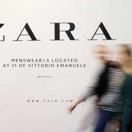 Un par de personas pasan por delante de un anuncio de una tienda de Zara, la principal enseña de Inditex, en Milán. REUTERS/Alessandro Garofalo