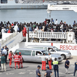 Dos coches funerarios aguardan a que varios oficiales desembarquen los cadáveres de dos inmigrantes a la llegada de la patrullera de la Guardia Costera Diciotti al puerto de Catania (Italia). EFE/ Orietta Scardino