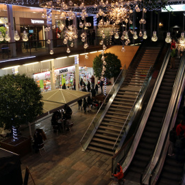 Compradors baixant per les escales mecàniques en una zona comercial del centre de Reus en el primer dissabte de la campanya de Nadal.