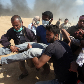 Varias personas trasladan un hombre herido durante las protestas del lunes en Gaza. - REUTERS