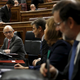 El ministro de Hacienda, Cristóbal Montoro, conversa, antes del comienzo de la sesión de control en el Pleno del Congreso, con el presidente del Gobierno, Mariano Rajoy, la vicepresidenta Soraya Saenz de Santamaria, y el titular de Justicia